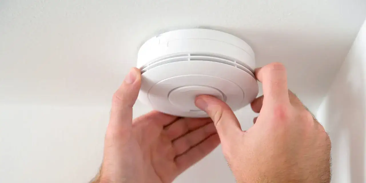 H&auml;nder monterar en vit r&ouml;kdetektor, en smart Google Nest Protect, i taket f&ouml;r &ouml;kad brands&auml;kerhet.