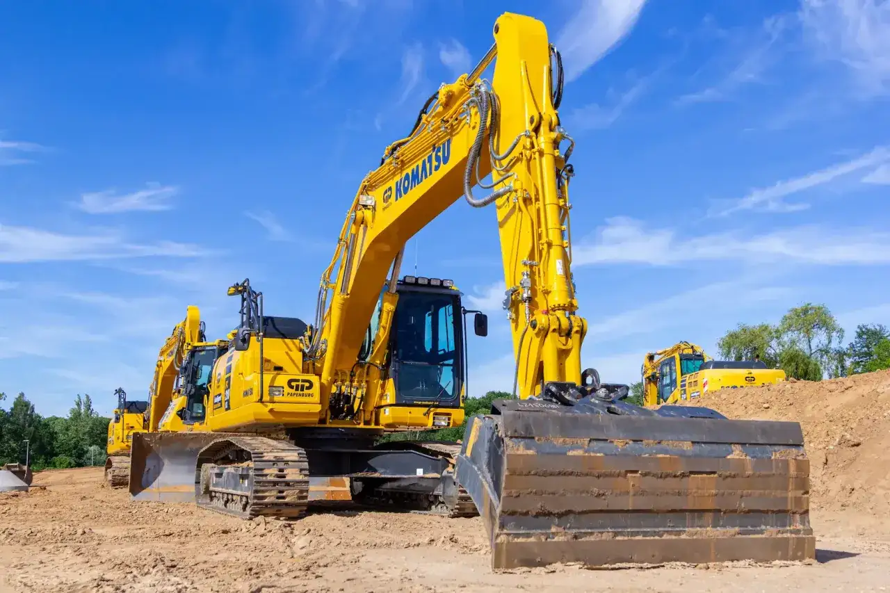 Żółte koparki Komatsu na placu budowy. Widoczny duży lemiesz do koparki, gotowy do pracy.
