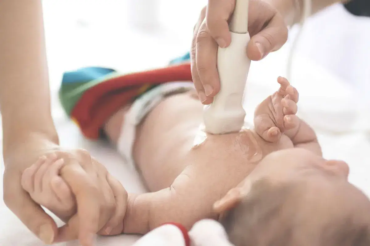 Ecografia neonatale per escludere meconio e danni cerebrali. Mani di un neonato tenute da un adulto.