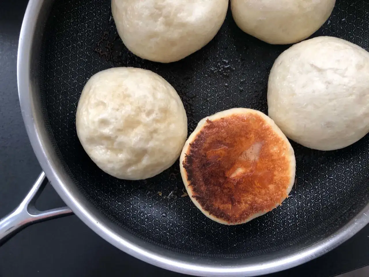 Dampfnudeln mit einer k&ouml;stlichen Salzkruste werden in einer Pfanne zubereitet.