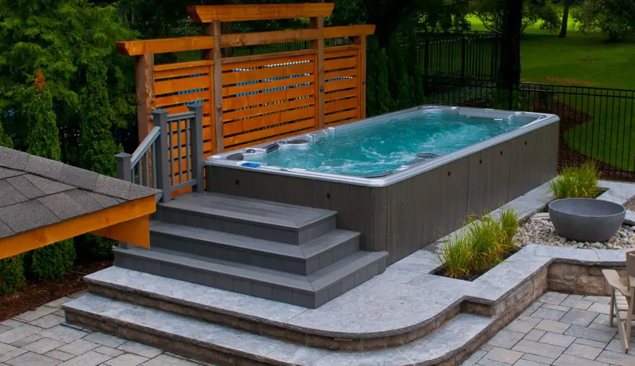 En lyxig swimspa med bubblande vatten, omgiven av en vacker trädgård. Perfekt swimspa inspiration för avkoppling och träning.