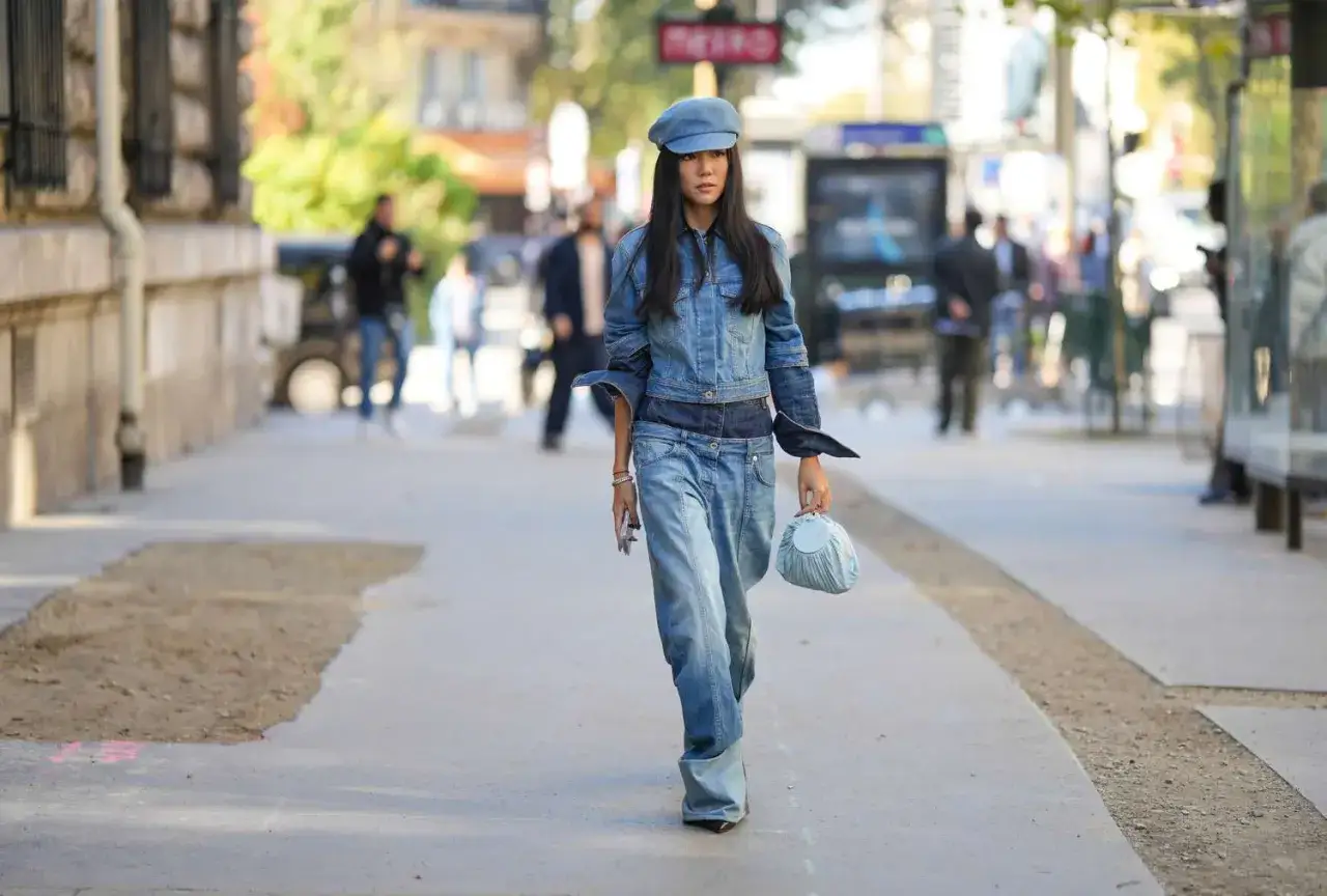 Frau in Jeansjacke und weiten Jeans, die fragt: welche hose zu jeansjacke? Sie tr&auml;gt eine blaue Schirmm&uuml;tze und eine kleine blaue Tasche.