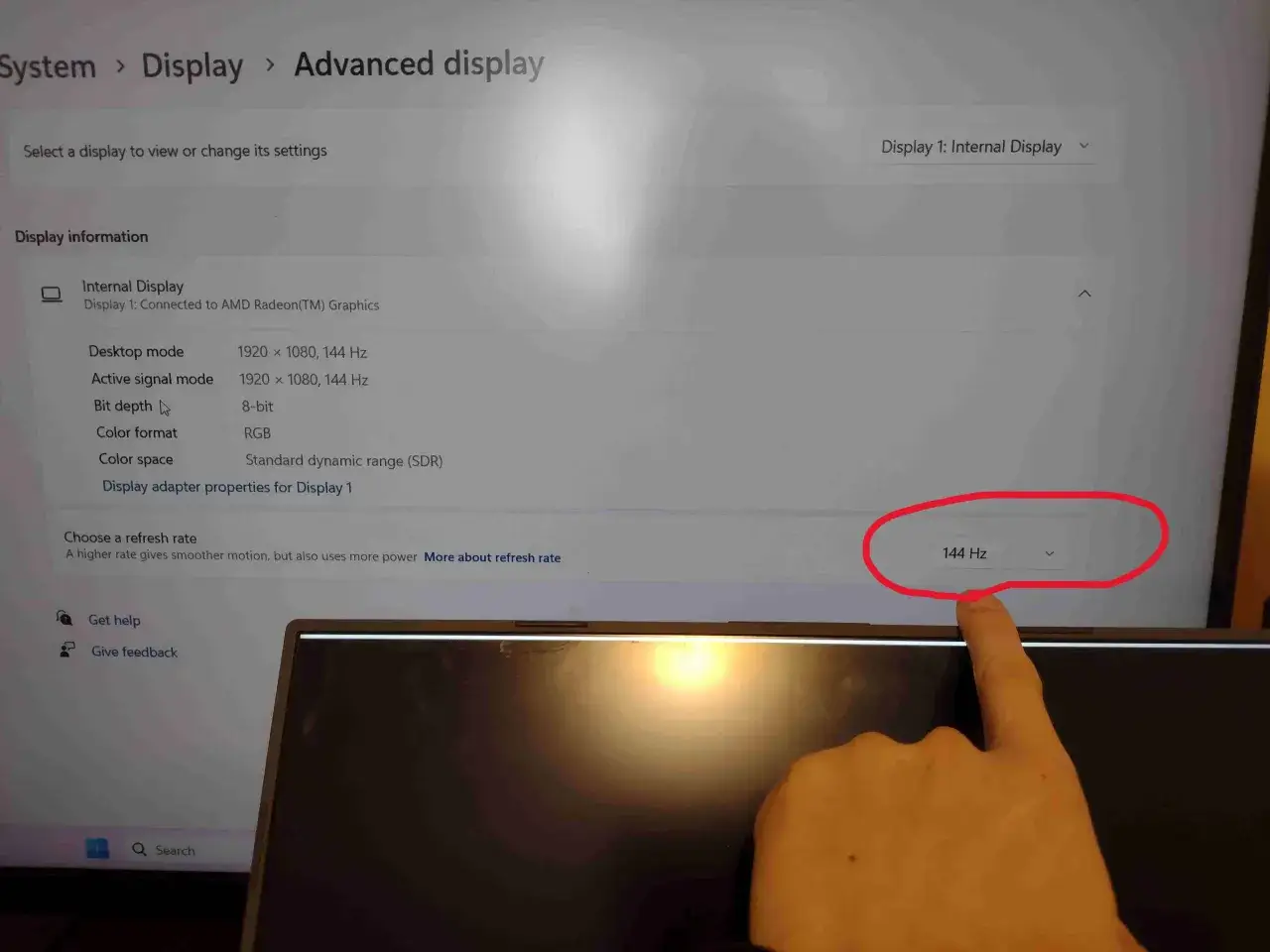 Ustawienia ekranu: rozdzielczość 1920x1080, 144 Hz. Palec wskazuje opcję odświeżania 144 Hz.
