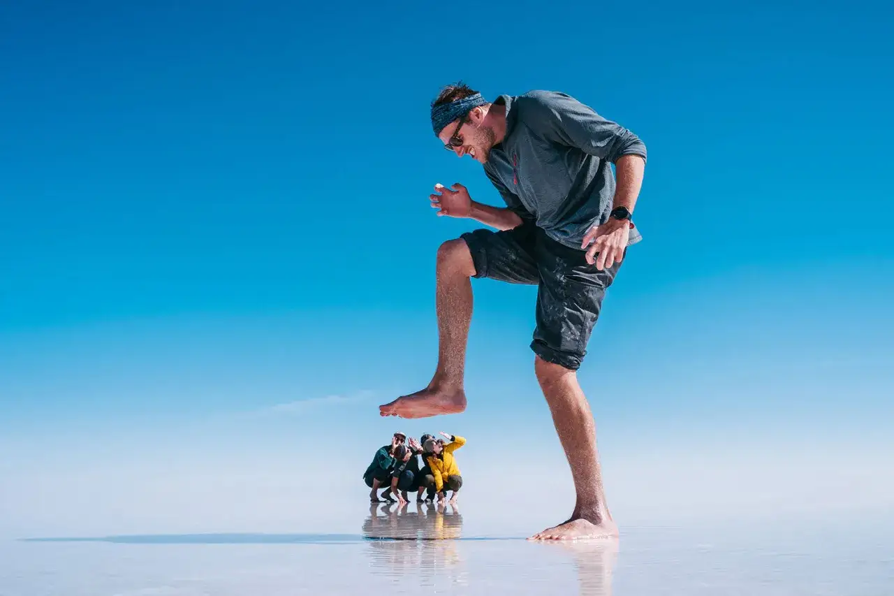 Un homme g&eacute;ant s'appr&ecirc;te &agrave; &eacute;craser trois personnes minuscules. Une excellente id&eacute;e photo perspective sur un fond bleu infini.