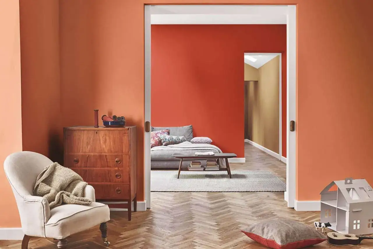 Un soggiorno accogliente con pareti arancioni, un divano letto e un mobile vintage. L'idea di dipingere casa con colori caldi.