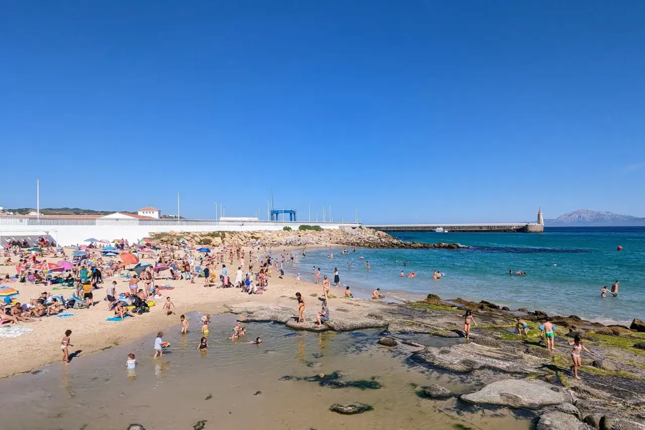 Sonniger Strandtag in C&aacute;diz mit Kindern. Familien planschen im flachen Wasser, sonnen sich und genie&szlig;en das Meer.