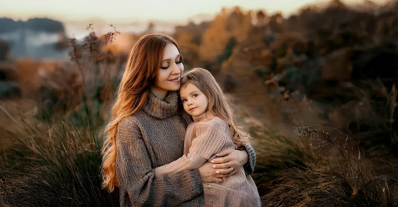 Dolce abbraccio tra madre e figlia in un campo dorato. Un momento prezioso catturato in queste foto di famiglia originali.
