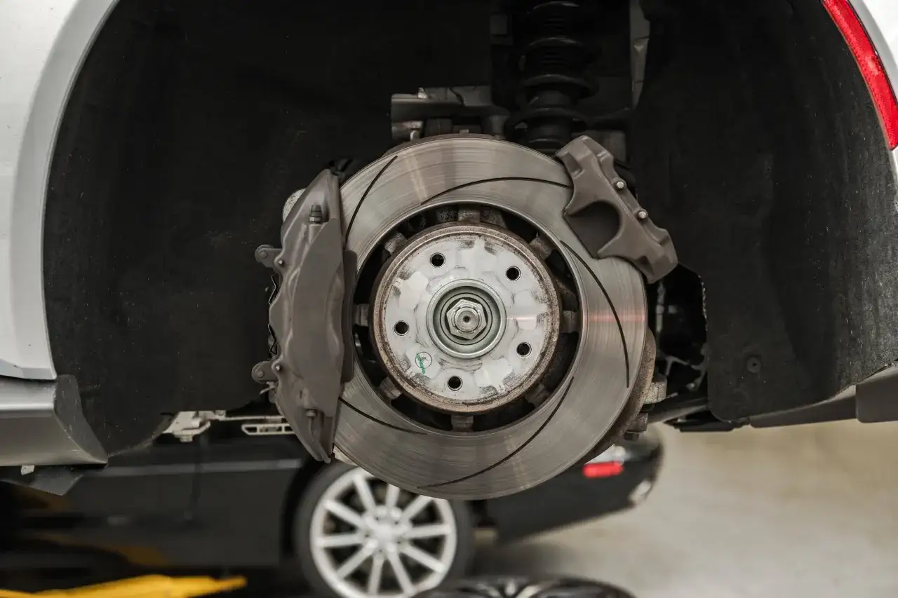 Nahaufnahme einer Bremsscheibe und eines Bremssattels. Das Auto klackert beim Bremsen, was auf ein Problem mit den Bremsen hindeuten könnte.