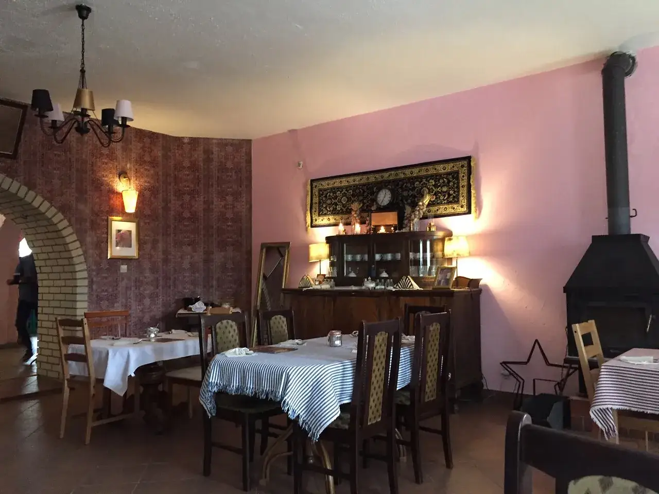 Wnętrze restauracji z różowymi ścianami, stołami nakrytymi obrusami i kominkiem. Czy zajazd babski istnieje?