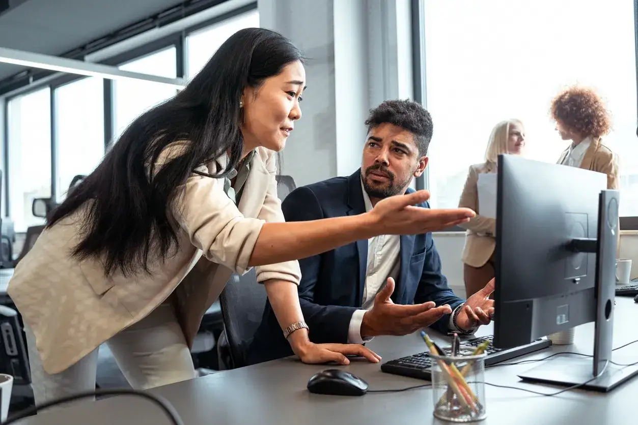 Colleagues collaborate, fostering a thriving mindset as they discuss a project on a computer screen.