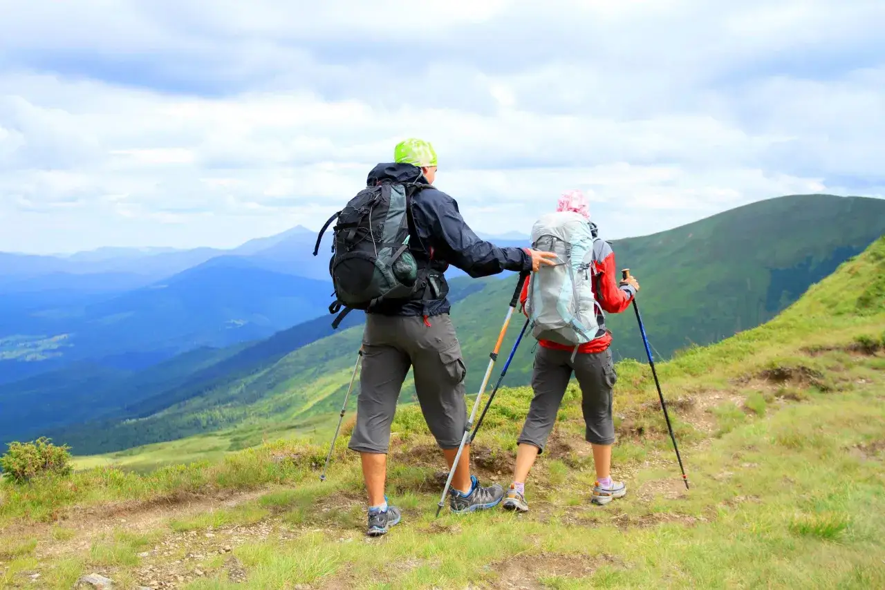 Para, jak chodzić z kijkami trekkingowymi, podziwia g&oacute;rski krajobraz.