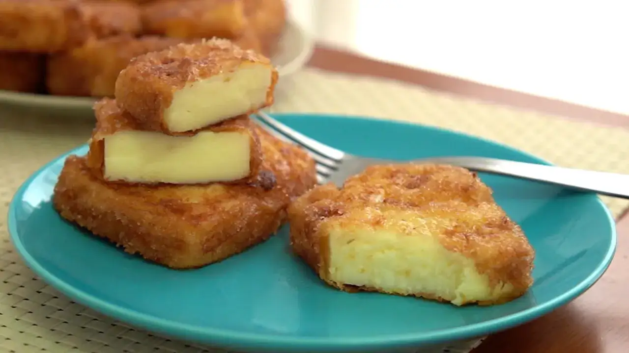 Deliciosa leche frita dorada y crujiente, con un interior cremoso, servida en un plato azul.