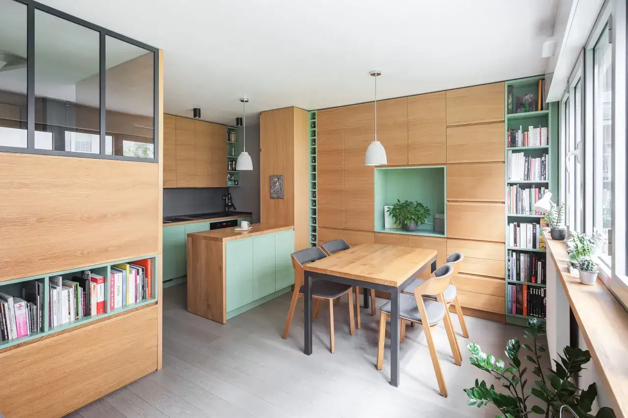 Aménagement studio 30m2 : cuisine, salle à manger et rangements intégrés en bois clair et menthe.