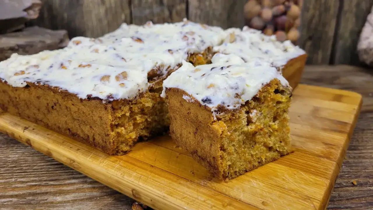 Szybkie i tanie ciasto marchewkowe z kremowym lukrem, pokrojone na desce. Idealne na deser!