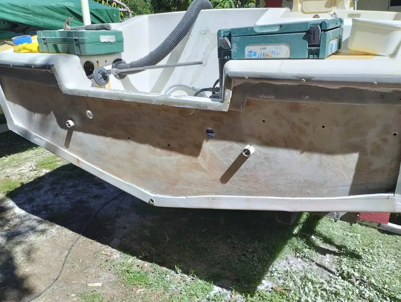 Pr&eacute;paration du tableau arri&egrave;re d'un bateau pour le refaire. Des outils et une bo&icirc;te de vis sont visibles.