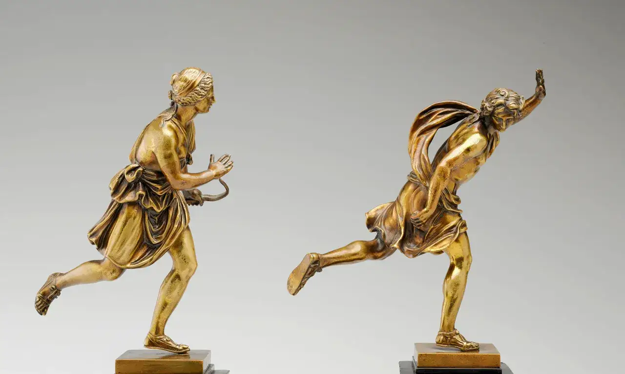Deux statuettes en bronze dor&eacute;s, repr&eacute;sentant une femme et un homme en pleine course, &eacute;voquant une performance artistique dynamique.