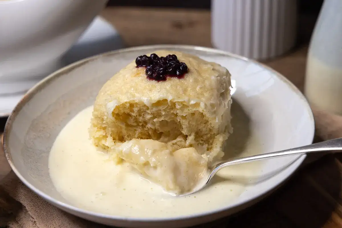 Ein fluffiger Dampfnudel, garniert mit Blaubeeren, in Vanillesauce. Ein köstliches Rezept für Dampfnudeln.