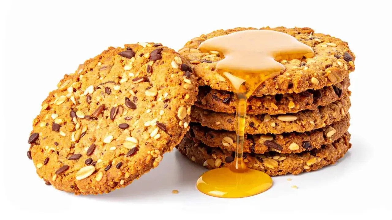 Galletas con copos de avena y semillas, cubiertas con miel dorada que gotea.
