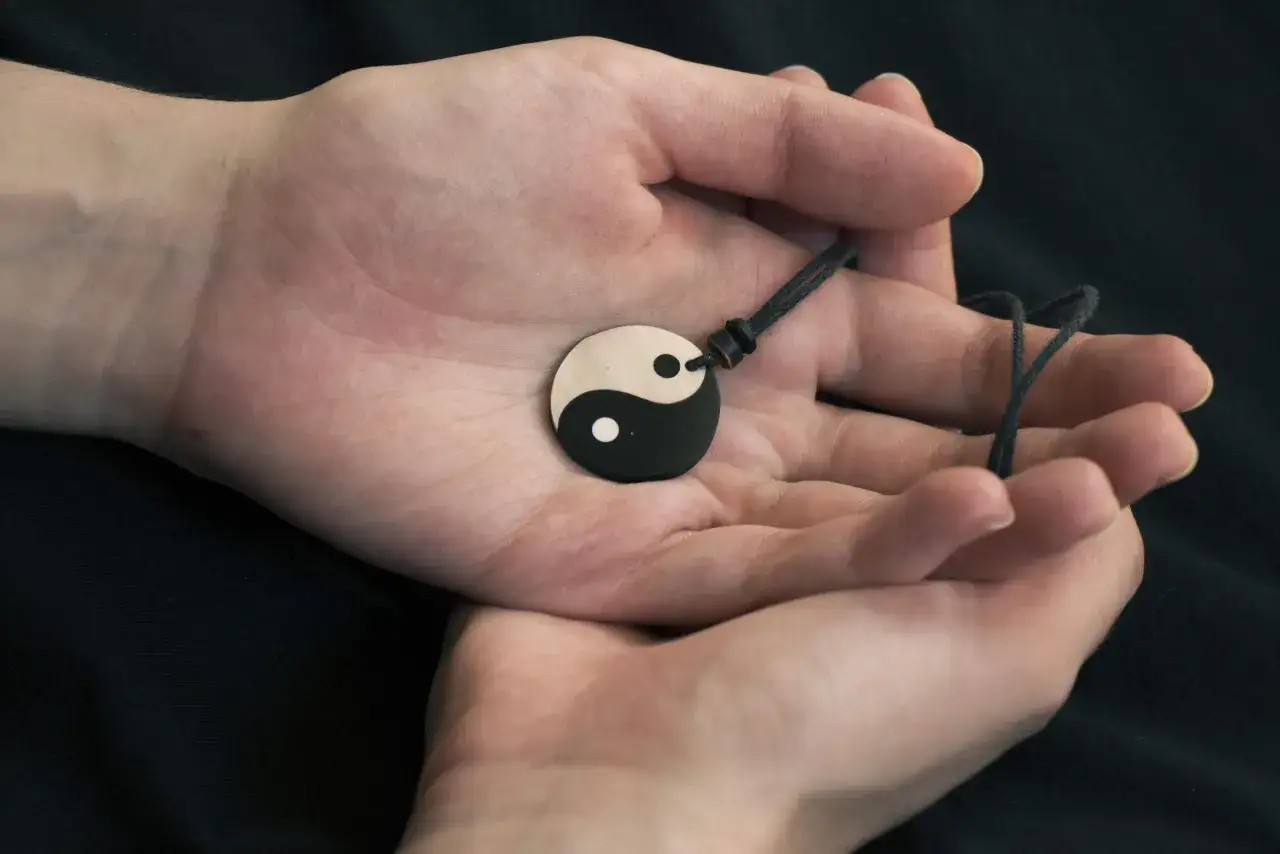 Dłonie trzymają medalion z symbolem Yin i Yang. To anielska liczba 2, symbol równowagi i harmonii.