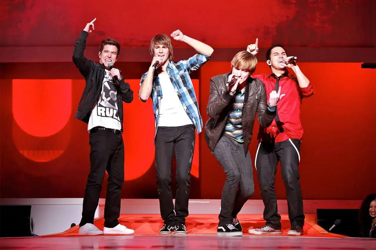Członkowie Big Time Rush na scenie, śpiewają z mikrofonami.