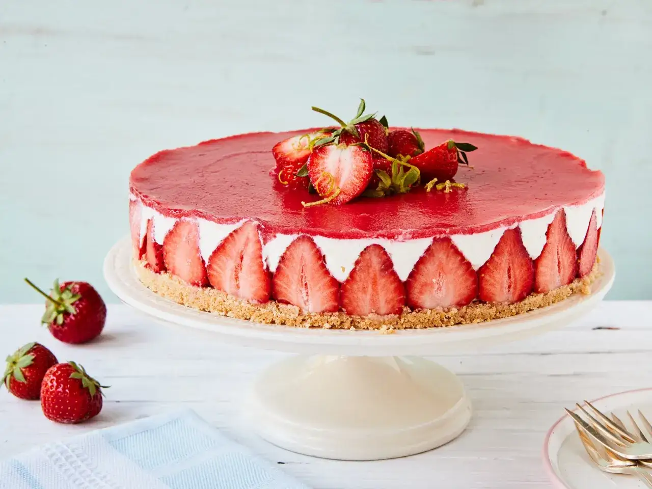 Kuchen ohne backen mit Keksboden: Ein köstlicher Erdbeerkuchen mit Frischkäsefüllung und rotem Fruchtspiegel, dekoriert mit frischen Erdbeeren.
