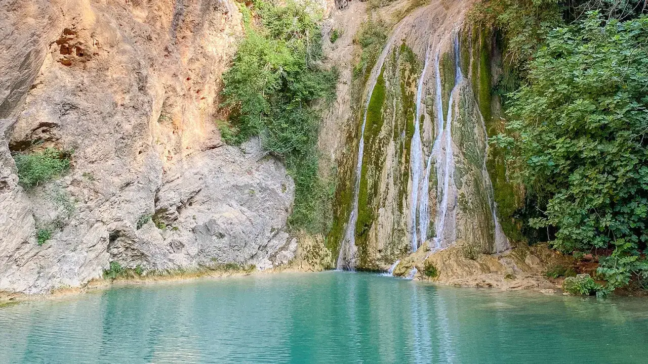 Magnifique cascade dans les gorges du Caramy, avec une eau turquoise et des falaises rocheuses verdoyantes.