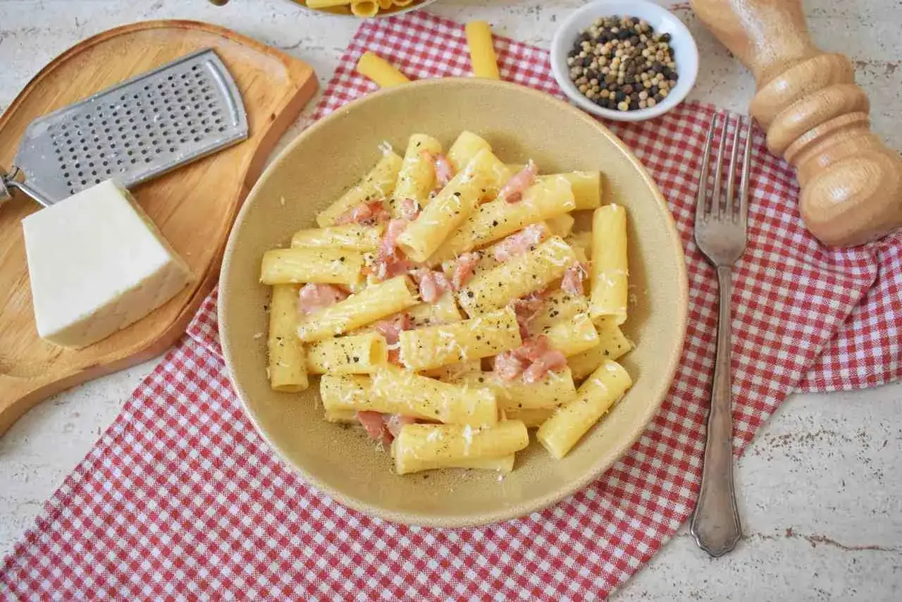 Pyszne danie pasta alla gricia z guanciale i pecorino romano, posypane świeżo mielonym pieprzem.