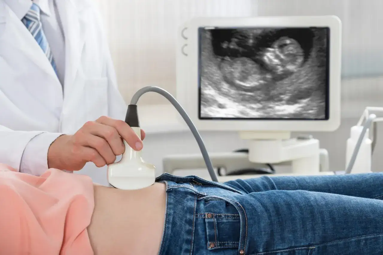 Lekarz wykonuje USG brzucha, na ekranie widać obraz płodu. To ważny **test pappa** dla przyszłych rodziców.