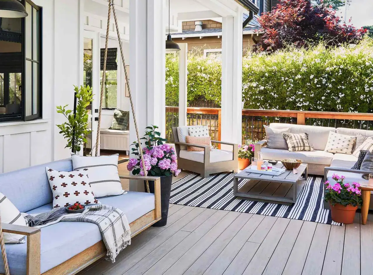 Gem&uuml;tliche Terrasse mit Schaukelbank, Sofa und Kissen. Mit Pflanzen und Teppich l&auml;sst sich die Terrasse gestalten mit wenig Geld.