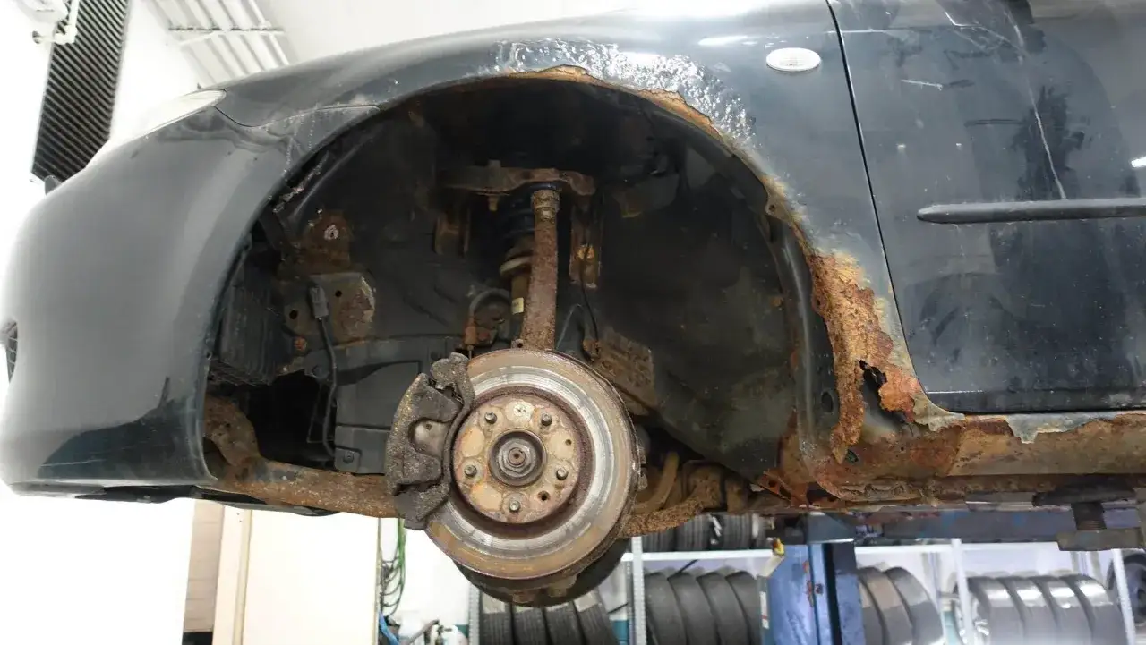 Mazda 6 problem: kraftig rostskada p&aring; sk&auml;rmkant och tr&ouml;skel. Bromsskiva och hjulupph&auml;ngning syns ocks&aring;.