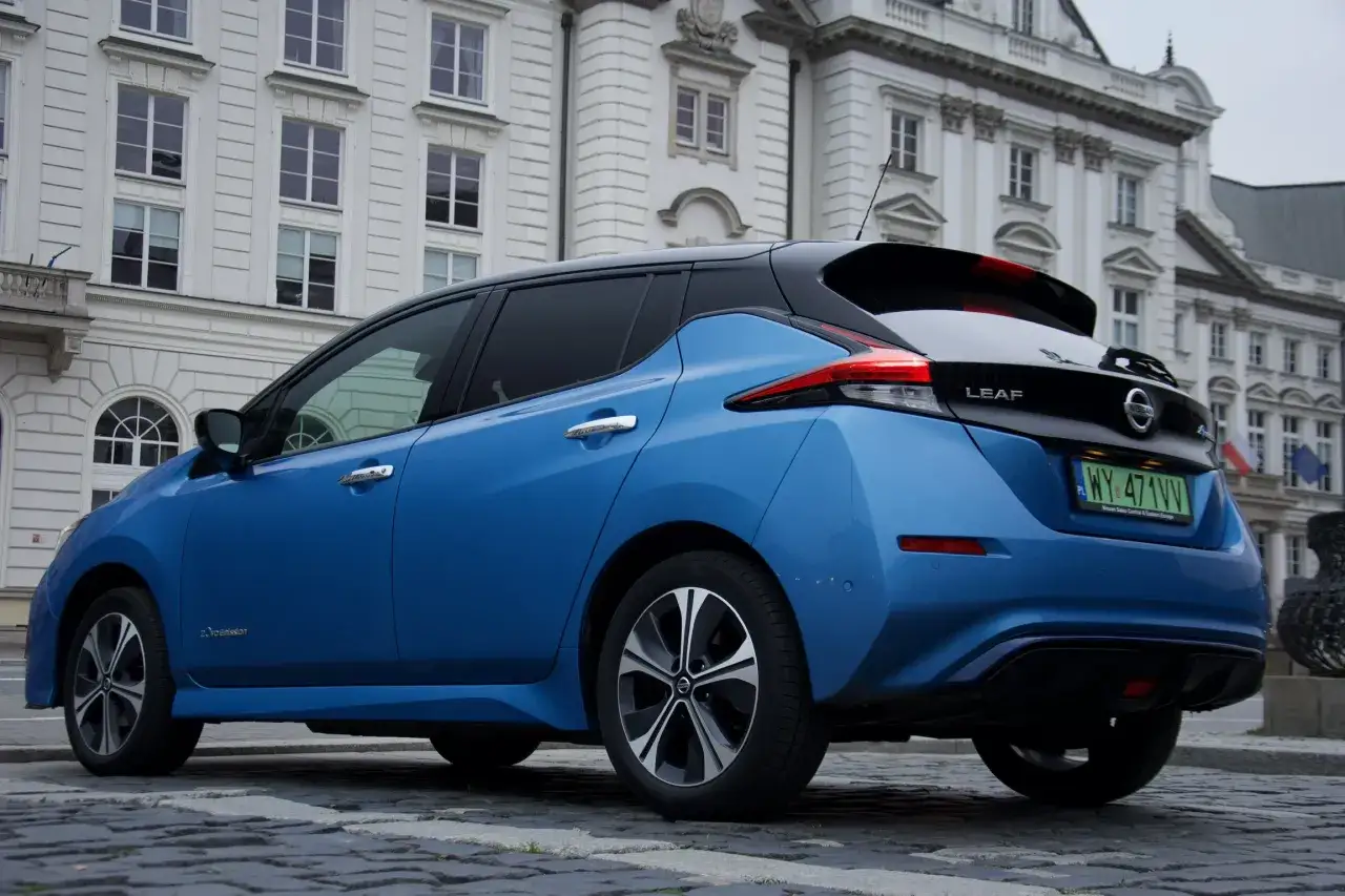Niebieski Nissan Leaf 2 stoi na bruku przed zabytkową kamienicą.