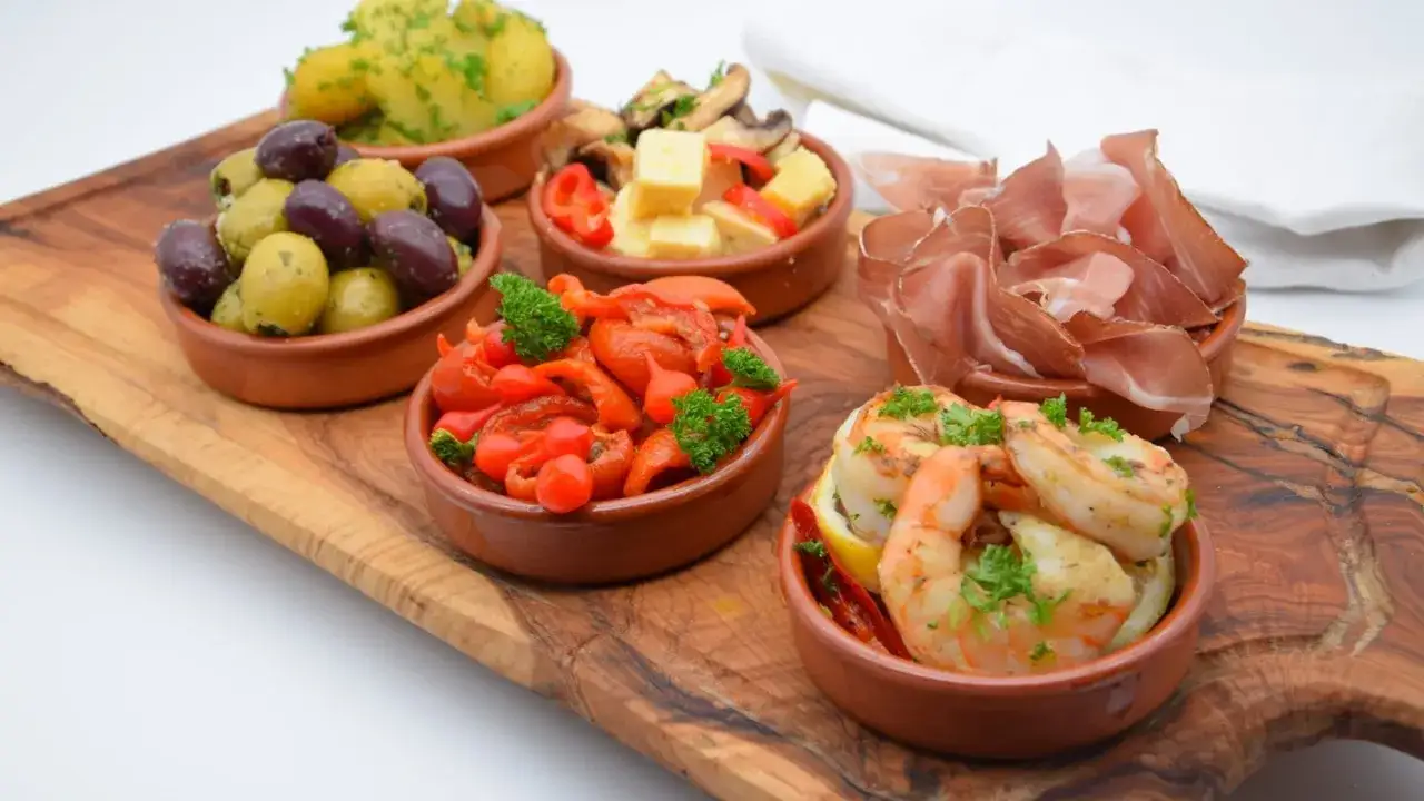 Kleine Schalen mit Oliven, Garnelen, Schinken und Paprika – perfekte Tapas-Rezepte für einen Abend mit Freunden.