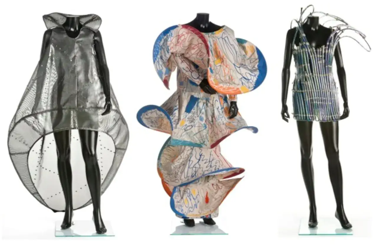 Tres vestidos de diseño: uno plateado futurista, otro con estampado de garabatos de **Manuel Piña**, y uno azul metálico con detalles de alambre.