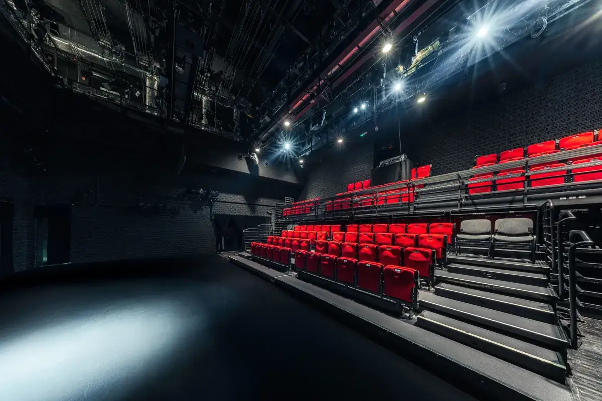 Pusta sala teatralna z rzędami czerwonych foteli i sceną gotową na przedstawienia teatralne w Warszawie.