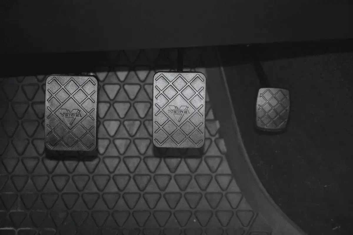 P&eacute;dales de voiture, dont l'embrayage qui patine. Le tapis de sol est textur&eacute;.