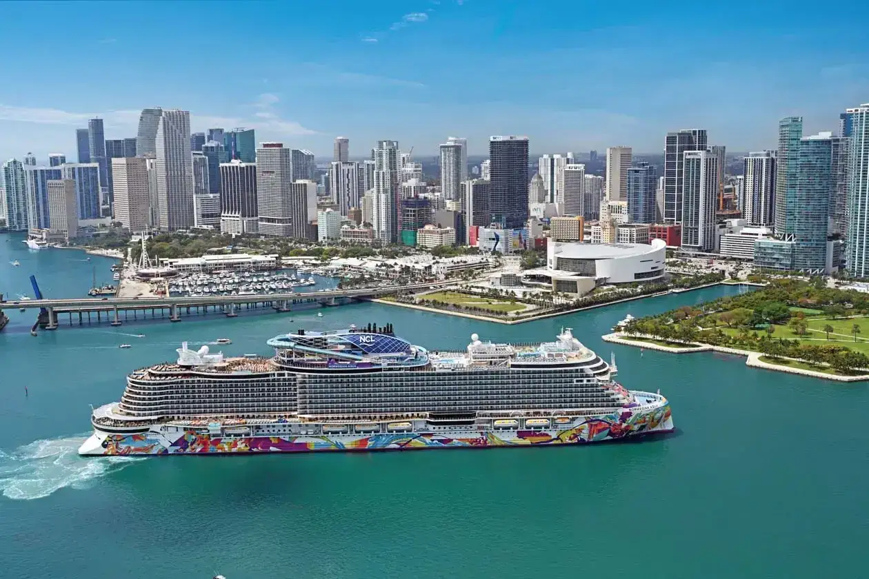 Nave da crociera colorata parte per una crociera caraibi, con skyline di Miami sullo sfondo.