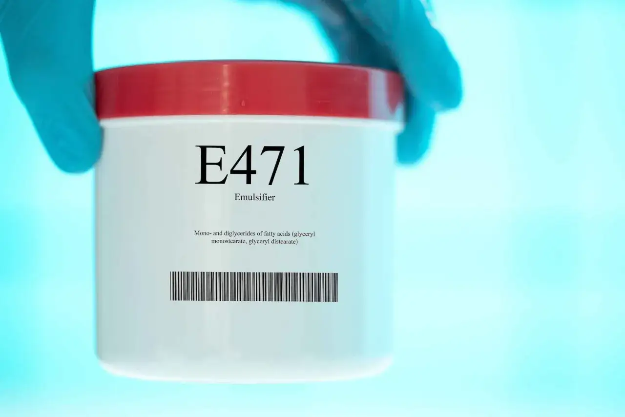 Main de laboratoire tenant un pot &eacute;tiquet&eacute; E471, &eacute;mulsifiant, monost&eacute;arate de glyc&eacute;rol.