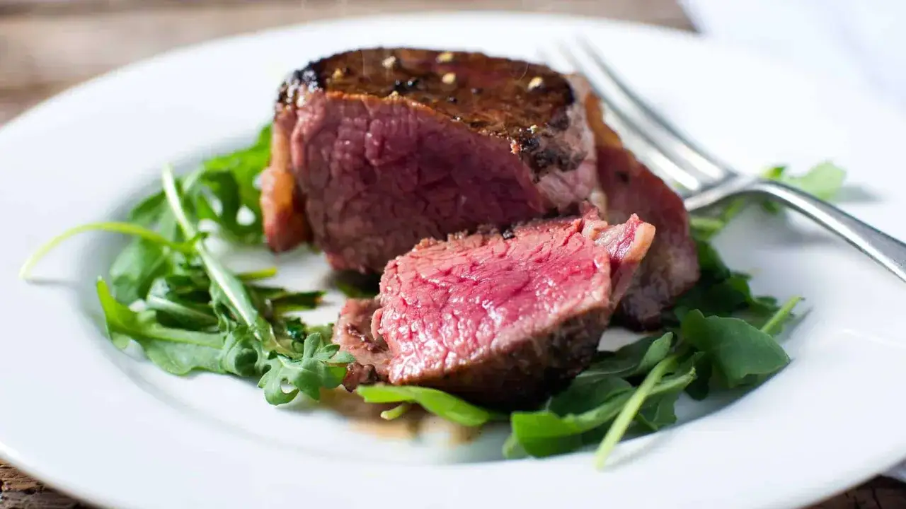 Un succulent filet mignon, coup&eacute; en deux, r&eacute;v&egrave;le sa tendret&eacute; ros&eacute;e, servi sur un lit de roquette fra&icirc;che.