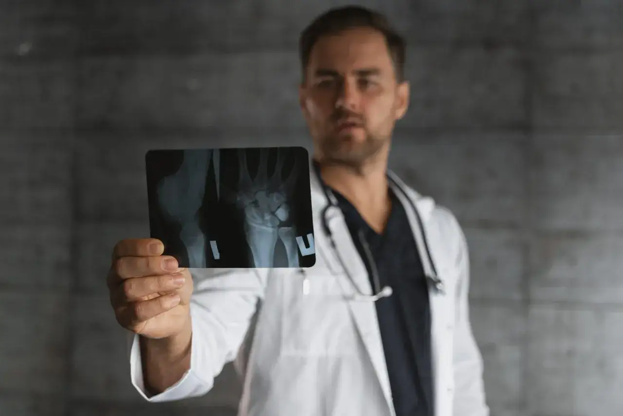 Medico con radiografia del polso, utile per capire la differenza tra fisiatra e ortopedico.