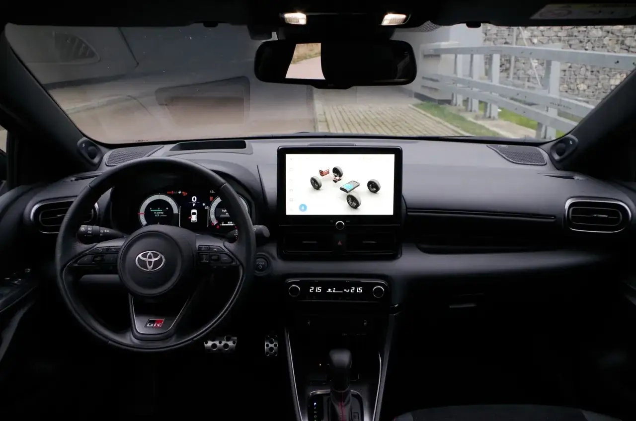 Wnętrze sportowego Toyota Yaris z ekranem multimedialnym pokazującym koła i nawigację.
