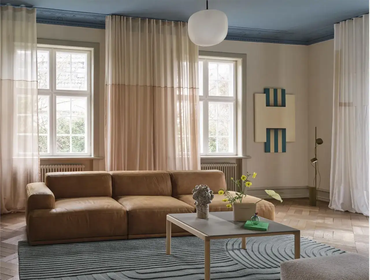 Gem&uuml;tliches Wohnzimmer mit brauner Ledercouch, blauem Deckenputz und Teppich, die **blau und braun kombinieren**.