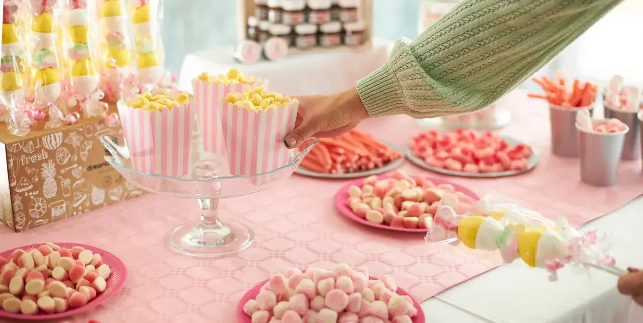 Mesa llena de dulces y tartas de gominolas, con palomitas y malvaviscos.