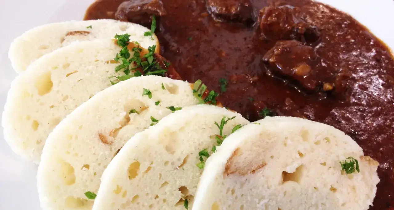 Gulasz z wołowiny z knedlikami, czyli klasyka tego, co jedzą Czesi. Danie ozdobione jest natką pietruszki.