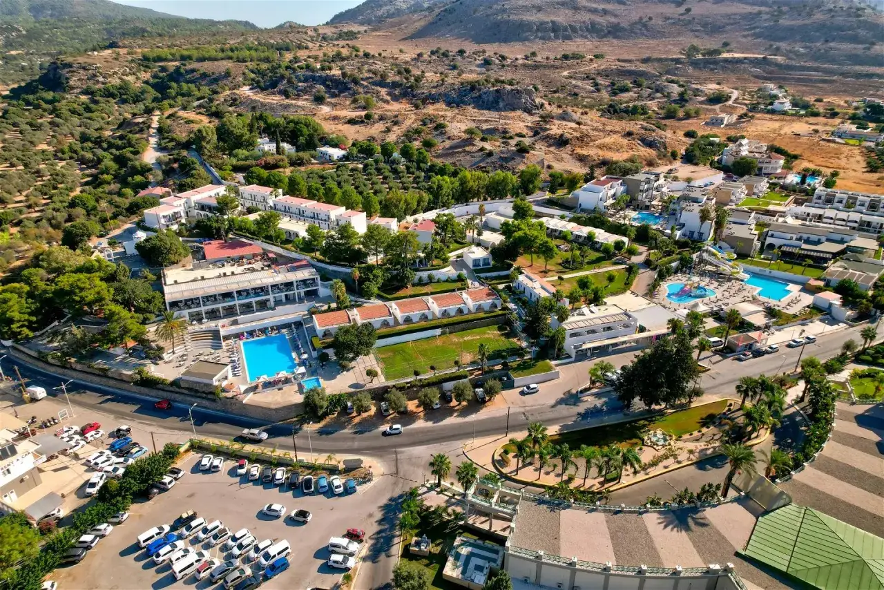 Widok z lotu ptaka na hotel Ellia Rodos z basenami, zjeżdżalniami i parkingiem pełnym samochod&oacute;w.