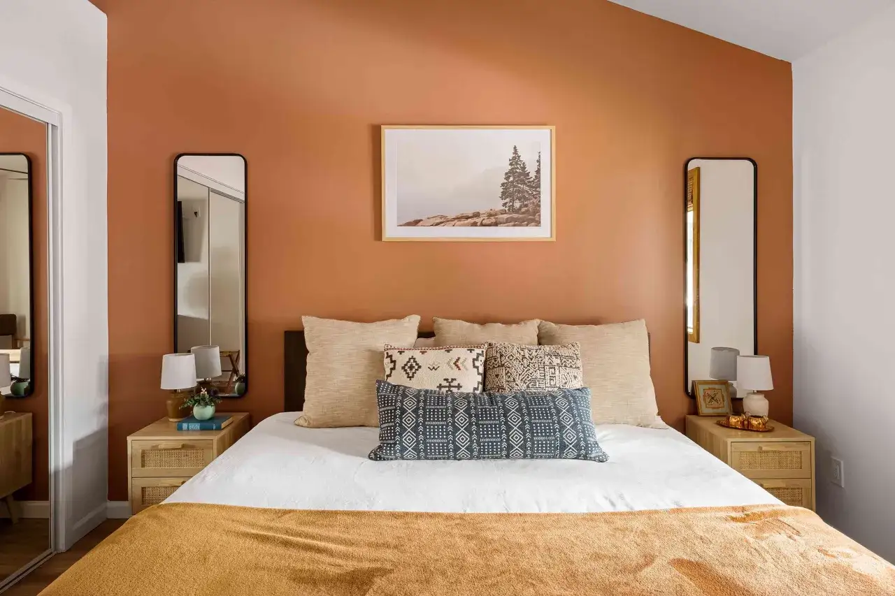 Une chambre chaleureuse avec des murs couleur terre cuite, un lit douillet et des coussins ethniques. L'idée parfaite pour peindre une chambre avec style.