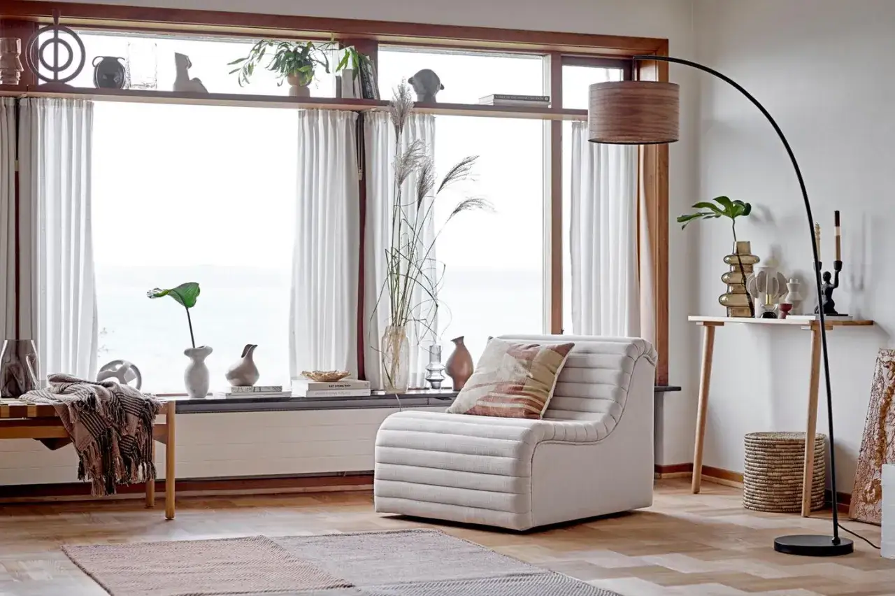 Gem&uuml;tliches Wohnzimmer mit einem bequemen Sessel und einem Bogenlampen. Das Panoramafenster dekorieren mit Vasen und Pflanzen.