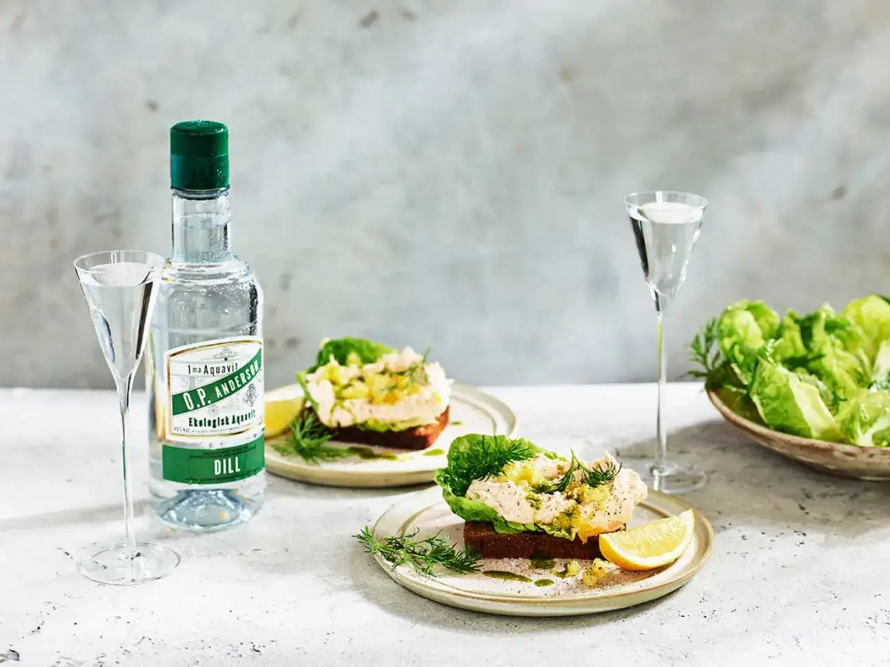 Två smörgåsar med gravad lax, dill och citron på mörkt bröd, serverade med O.P. Anderson Dill akvavit och sallad.