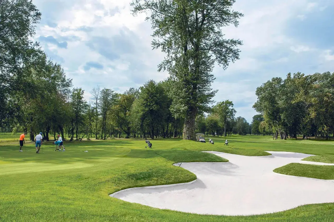 Gracze na polu golfowym, piękny dzień na first warsaw golf. Piaskownica i wózek golfowy w tle.