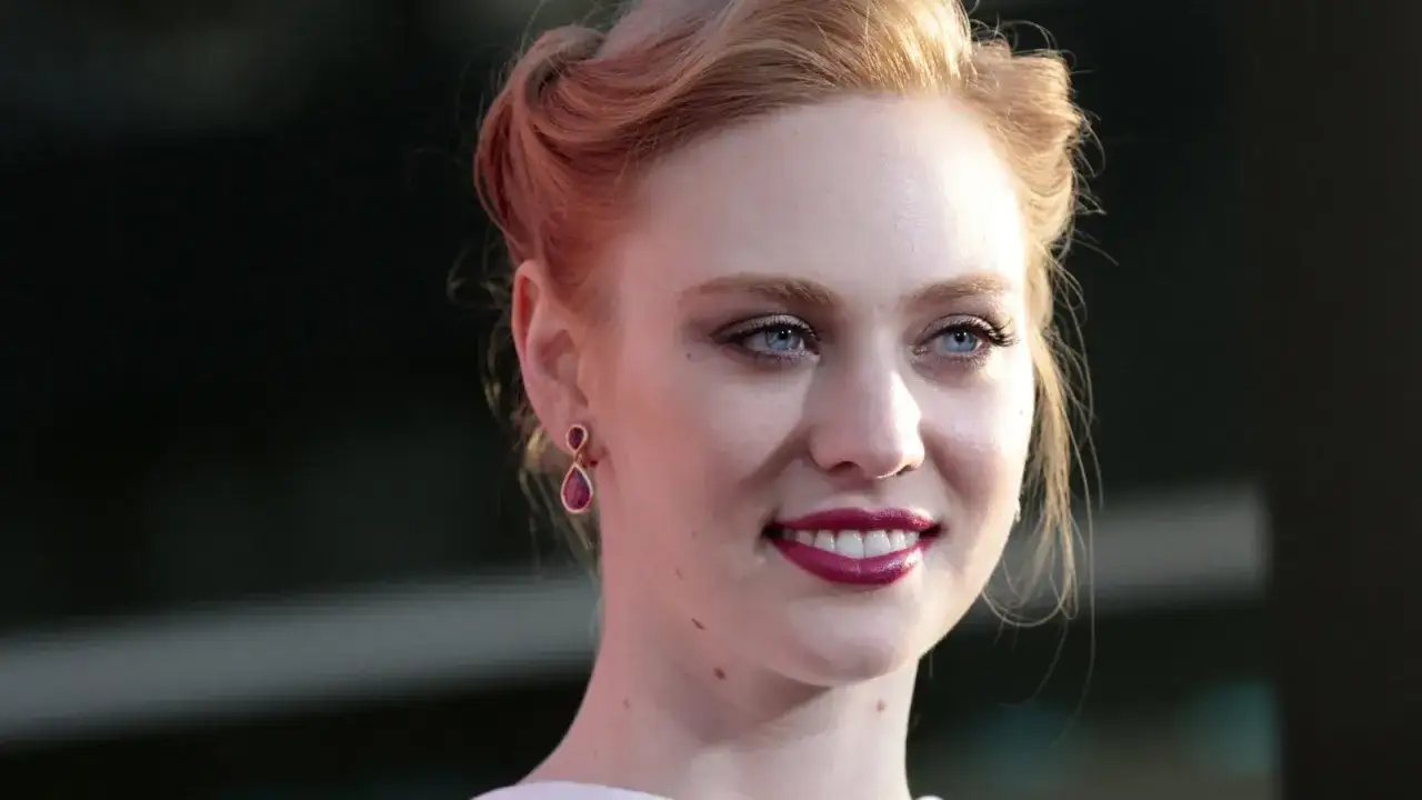 La belle Deborah Ann Woll, qui a jou&eacute; Karen Page, sourit avec des boucles blondes et des boucles d'oreilles en forme de goutte.