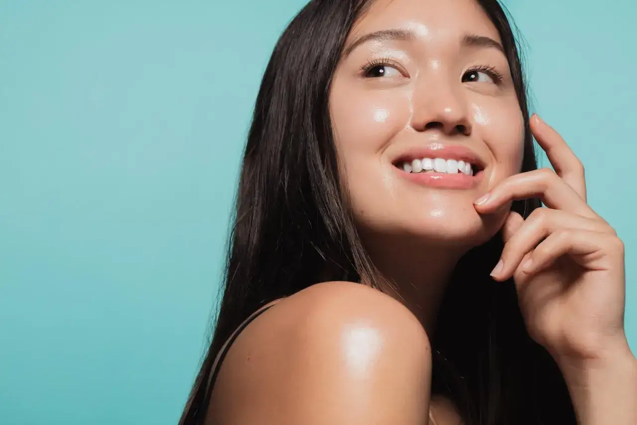Una mujer sonr&iacute;e con un radiante **efecto glow cara**, su piel luce hidratada y luminosa.